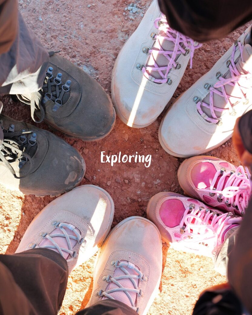 Man in swim trunks holds a baby in a blue life jacket in shallow water.