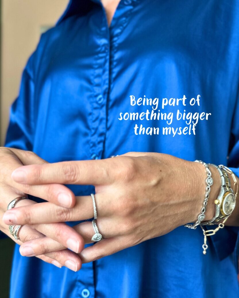 Man in swim trunks holds a baby in a blue life jacket in shallow water.