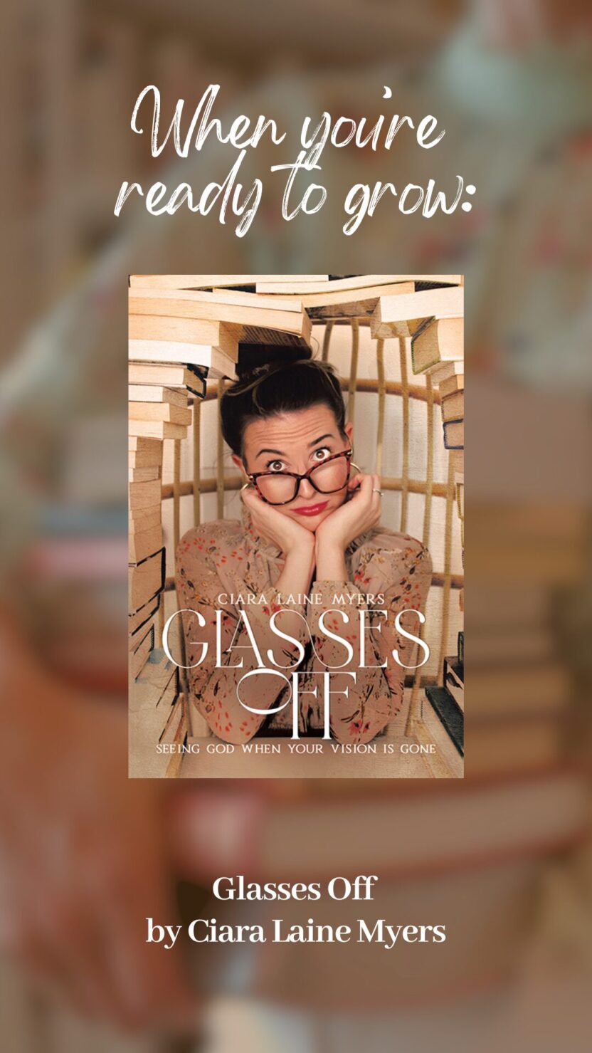 Man in swim trunks holds a baby in a blue life jacket in shallow water.