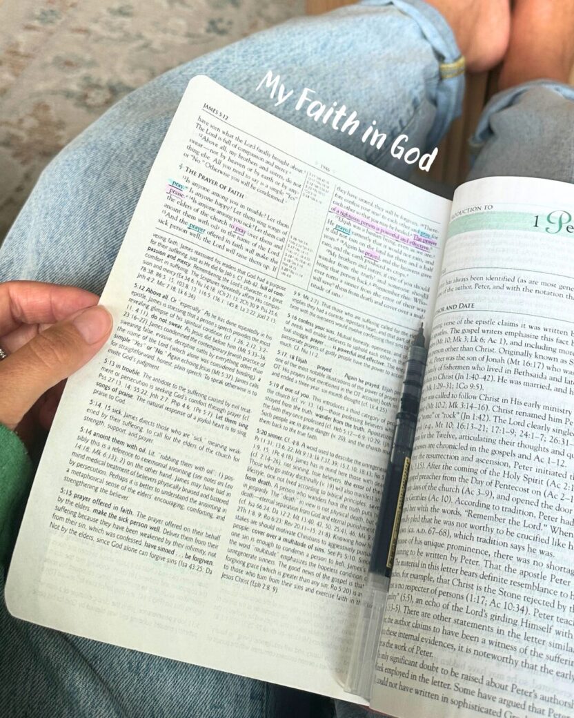Man in swim trunks holds a baby in a blue life jacket in shallow water.