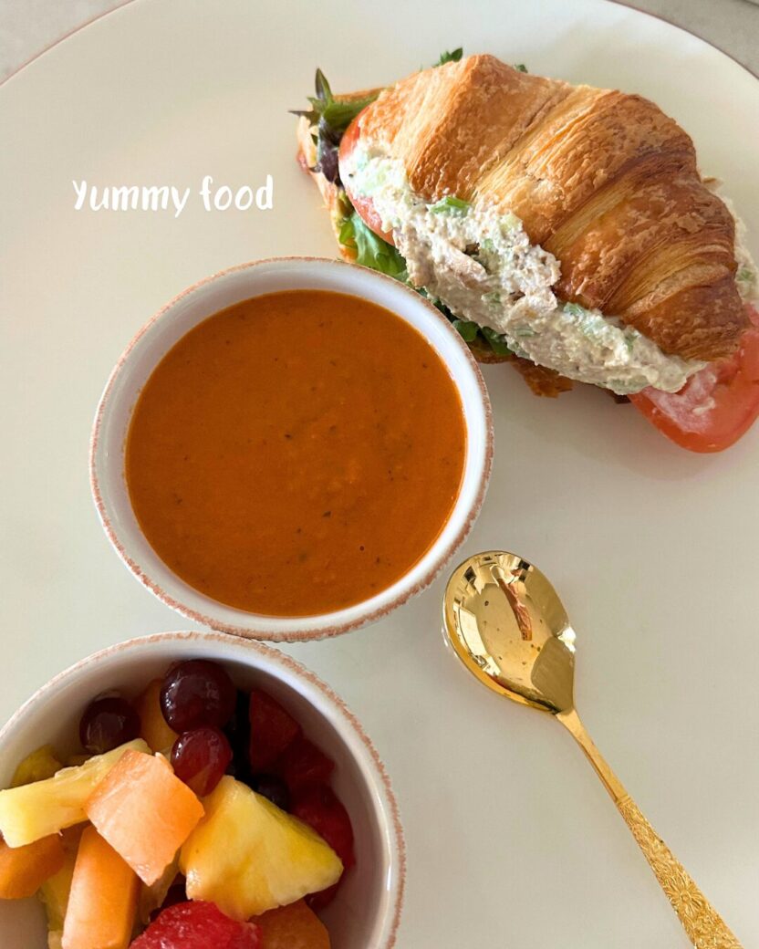 Man in swim trunks holds a baby in a blue life jacket in shallow water.