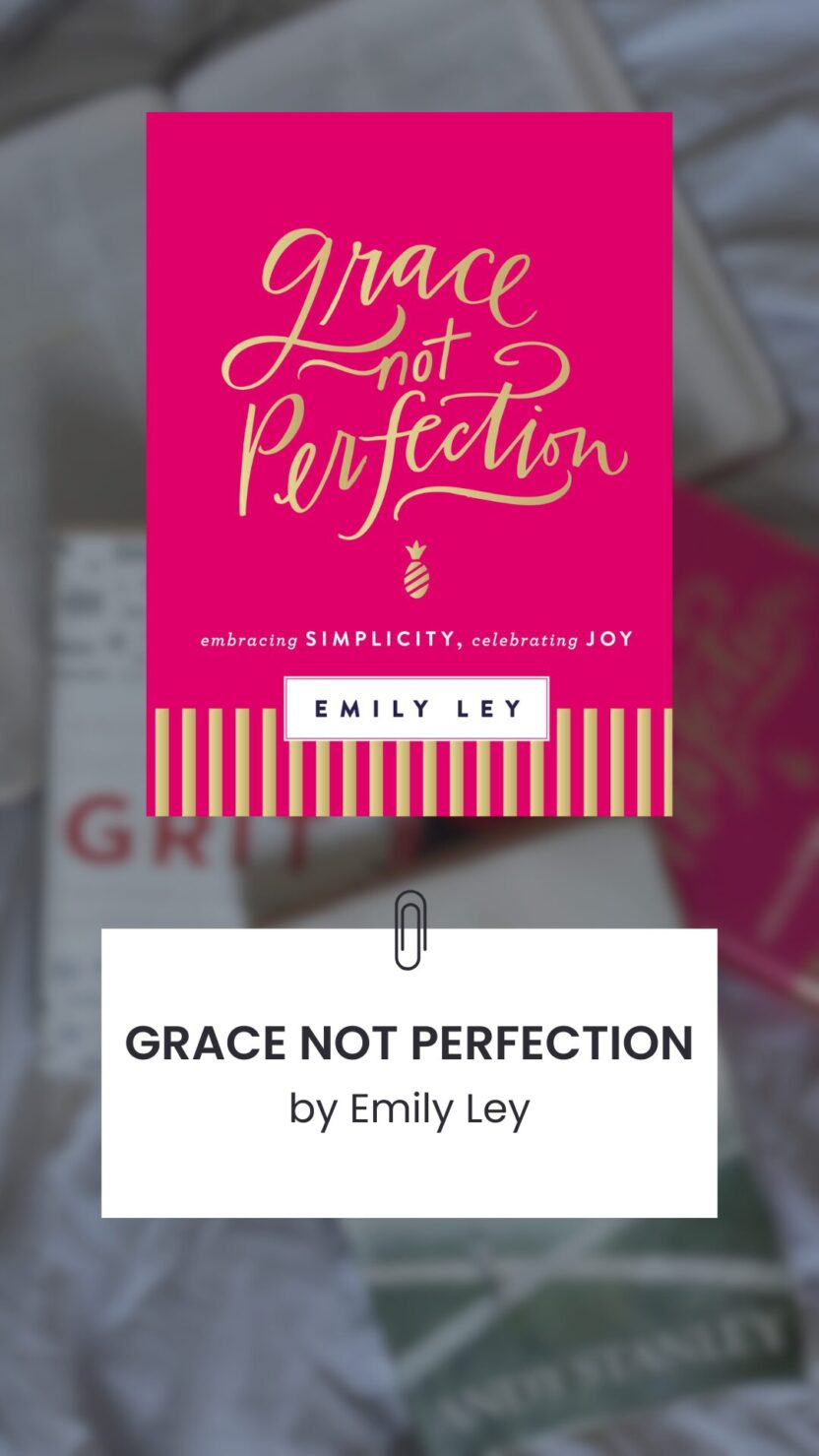 Man in swim trunks holds a baby in a blue life jacket in shallow water.