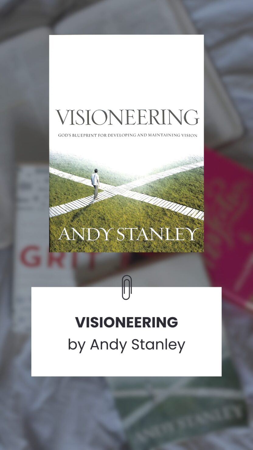 Man in swim trunks holds a baby in a blue life jacket in shallow water.