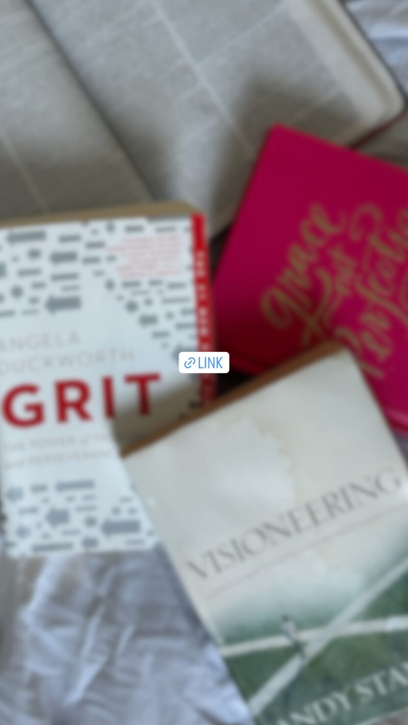 Man in swim trunks holds a baby in a blue life jacket in shallow water.