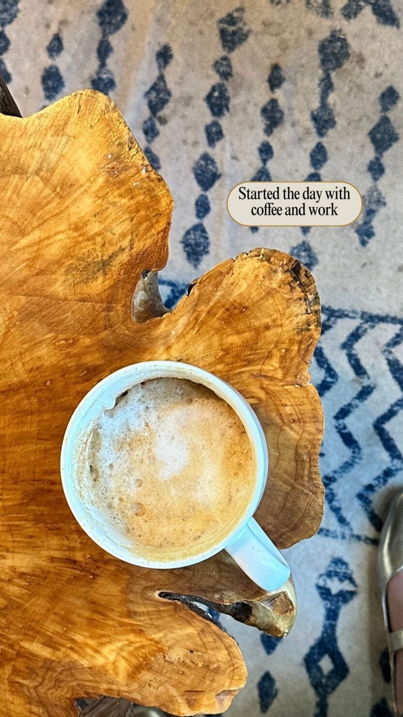 Man in swim trunks holds a baby in a blue life jacket in shallow water.