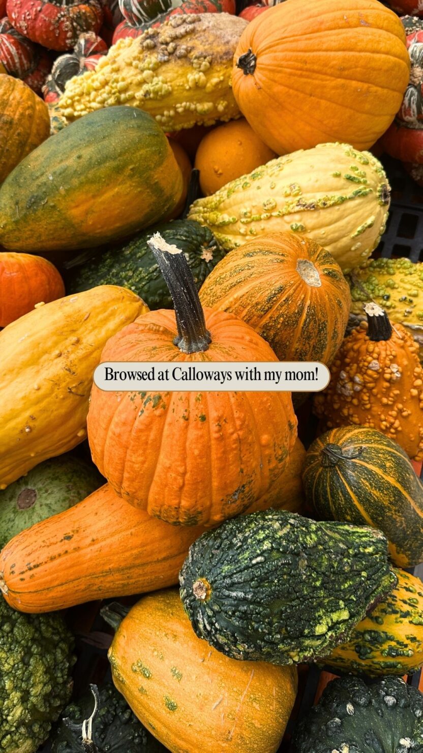 Man in swim trunks holds a baby in a blue life jacket in shallow water.