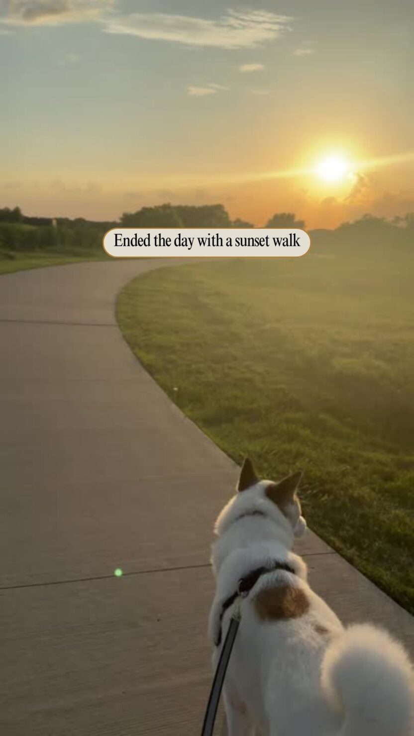 Man in swim trunks holds a baby in a blue life jacket in shallow water.