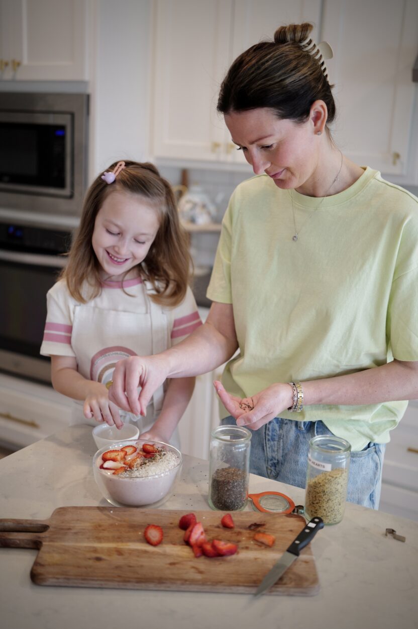 mother and daughter in kitchen chopping fruit and making a protein smoothie bowl