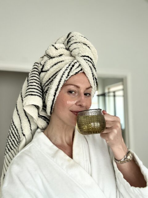 Woman in robe with towel drinking tea.
