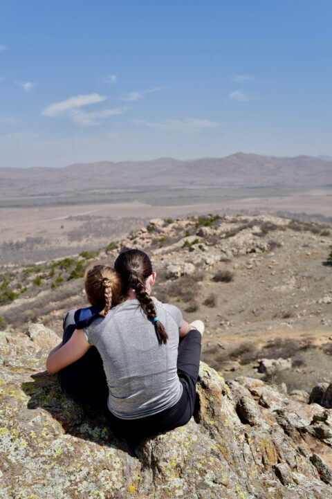 Two people sitting on rocky hilltop.