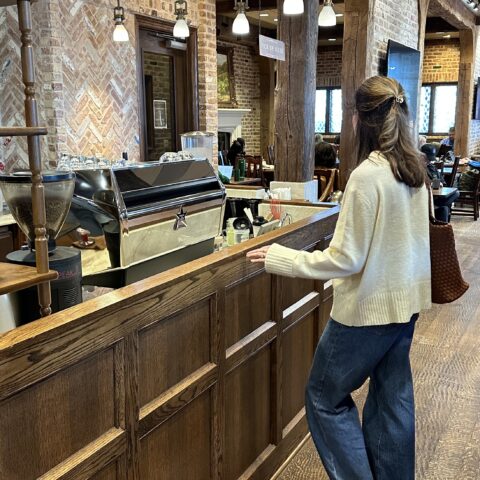 Woman standing at a rustic coffee counter.